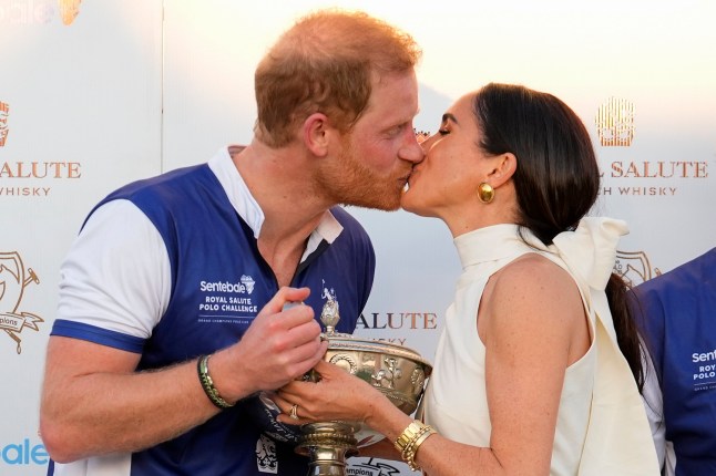 Britain's Prince Harry and wife Meghan Markle, Duchess of Sussex, kiss as she presents his polo team with the trophy for winning the 2024 Royal Salute Polo Challenge to Benefit Sentebale