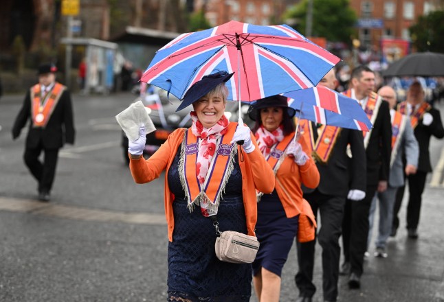BELFAST, NORTHERN IRELAND - JULY 12: A female Orange lodge member waves as she takes part in the parade on July 12, 2023 in Belfast, Northern Ireland. The marches celebrate the victory of the protestant King William of Orange over the catholic King James at the Battle of the Boyne in 1690. (Photo by Charles McQuillan/Getty Images)